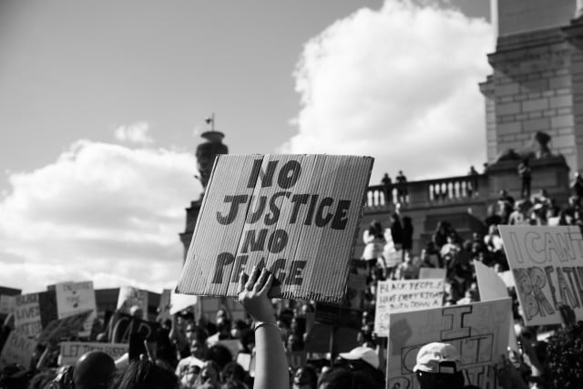 Black and white photo of signs displaying No Justice, No Peace