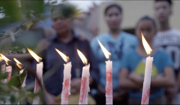 Ignited candles stand in front of a group of people in the background.